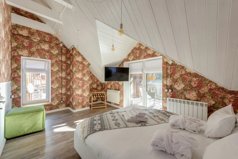 a bed room with a neatly made bed and a flat screen tv, by Julia Pishtar, unsplash, art nouveau, chalet, decorated with russian motifs, with matte white angled ceiling, cozy calm! fabrics textiles