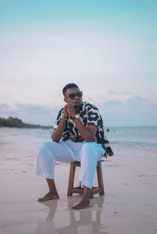 a man sitting on a chair on a beach, an album cover, inspired by Barthélemy Menn, pexels contest winner, hurufiyya, casual pose, mkbhd, profile image, wearing shades