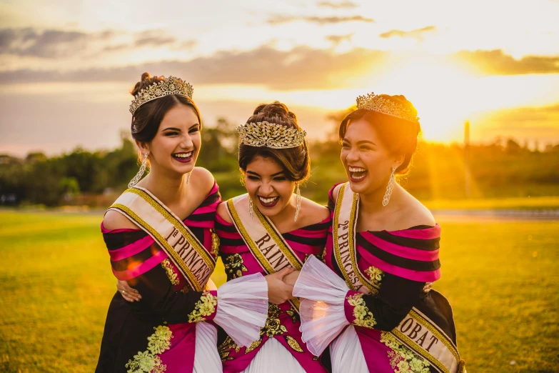 a group of three women standing next to each other, pexels contest winner, happening, baroque hibiscus queen, sunset lighting, gold tiara, south east asian with long