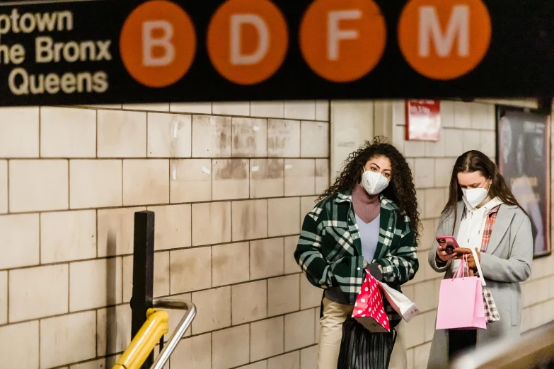 a couple of women standing next to each other on a subway platform, a photo, by Meredith Dillman, pexels, graffiti, wearing facemask, 2 5 6 x 2 5 6 pixels, mta subway entrance, people shopping