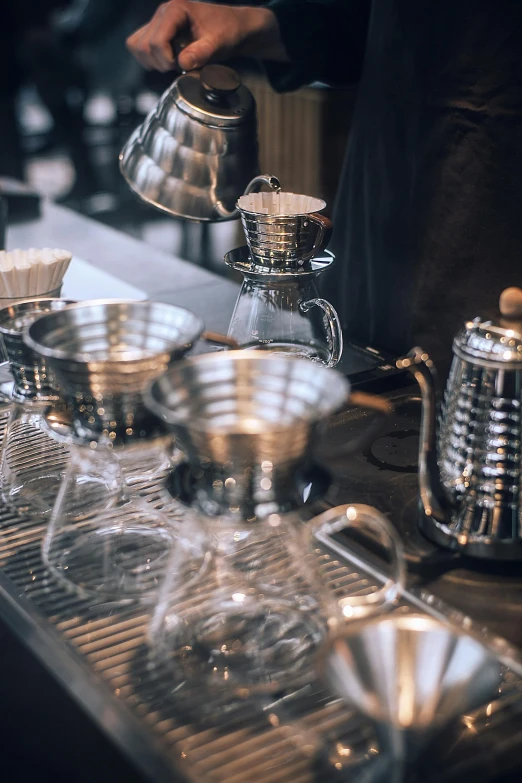 a person pouring a cup of coffee on top of a counter, by Adam Marczyński, pexels contest winner, steel plating, lots of beakers, featuring rhodium wires, banner