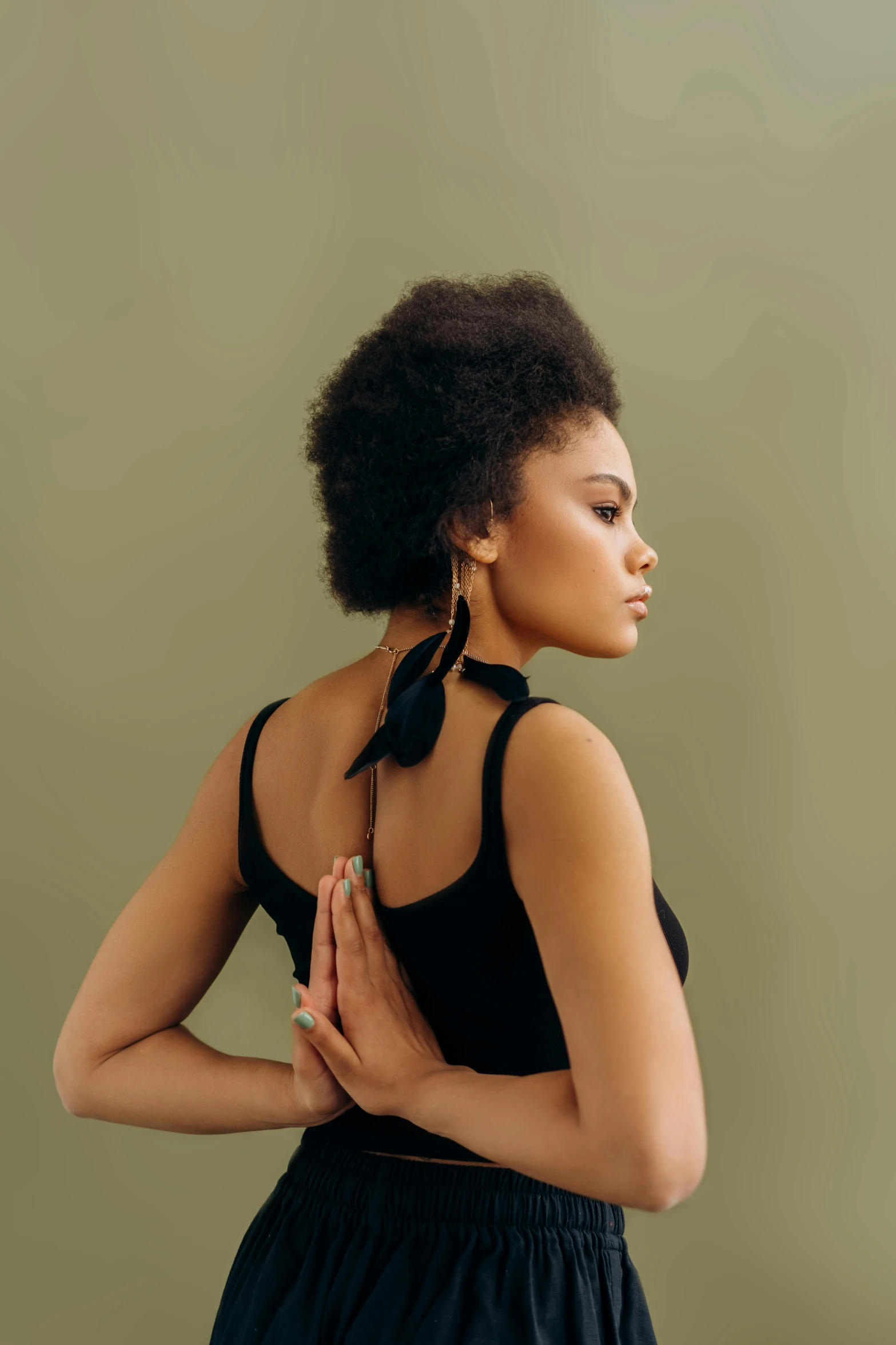 a woman in a black dress posing for a picture, an album cover, trending on pexels, arabesque, praying posture, natural hair, hands in her hair. side-view, portrait sophie mudd