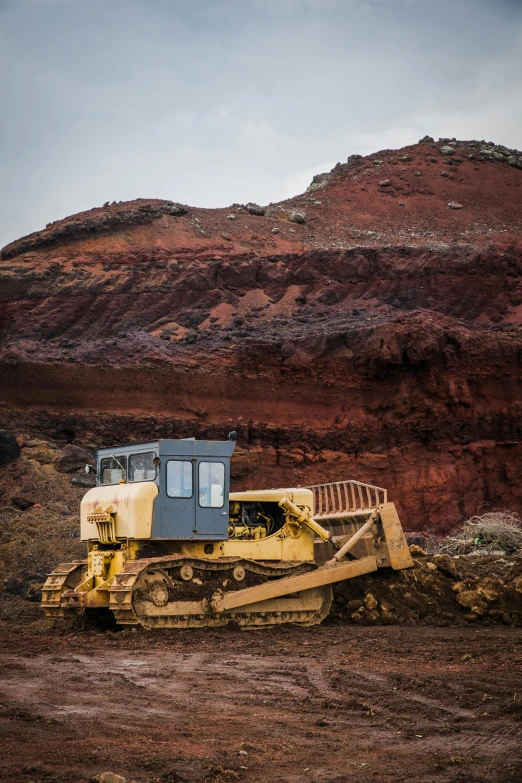 a bulldozer sitting on top of a dirt field, in a volcano, red iron oxide, looking serious, mining