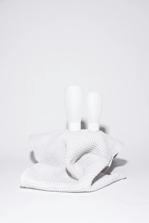 a couple of toothbrushes sitting on top of a towel, a marble sculpture, by Carey Morris, minimalism, holding wine bottle, in front of white back drop, wearing white cloths, subtle pattern