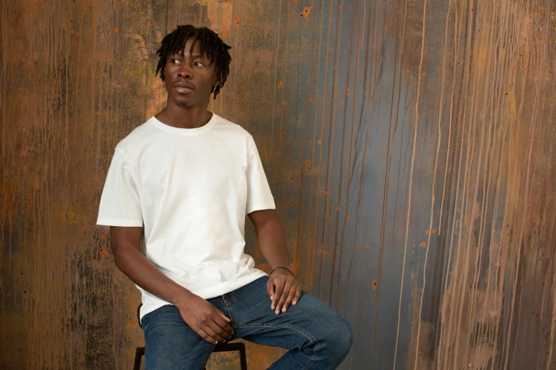 a man sitting on a stool in front of a wall, inspired by Thomas Blackshear, trending on unsplash, hyperrealism, plain white tshirt, chief keef, studio portrait photo, around 1 9 years old