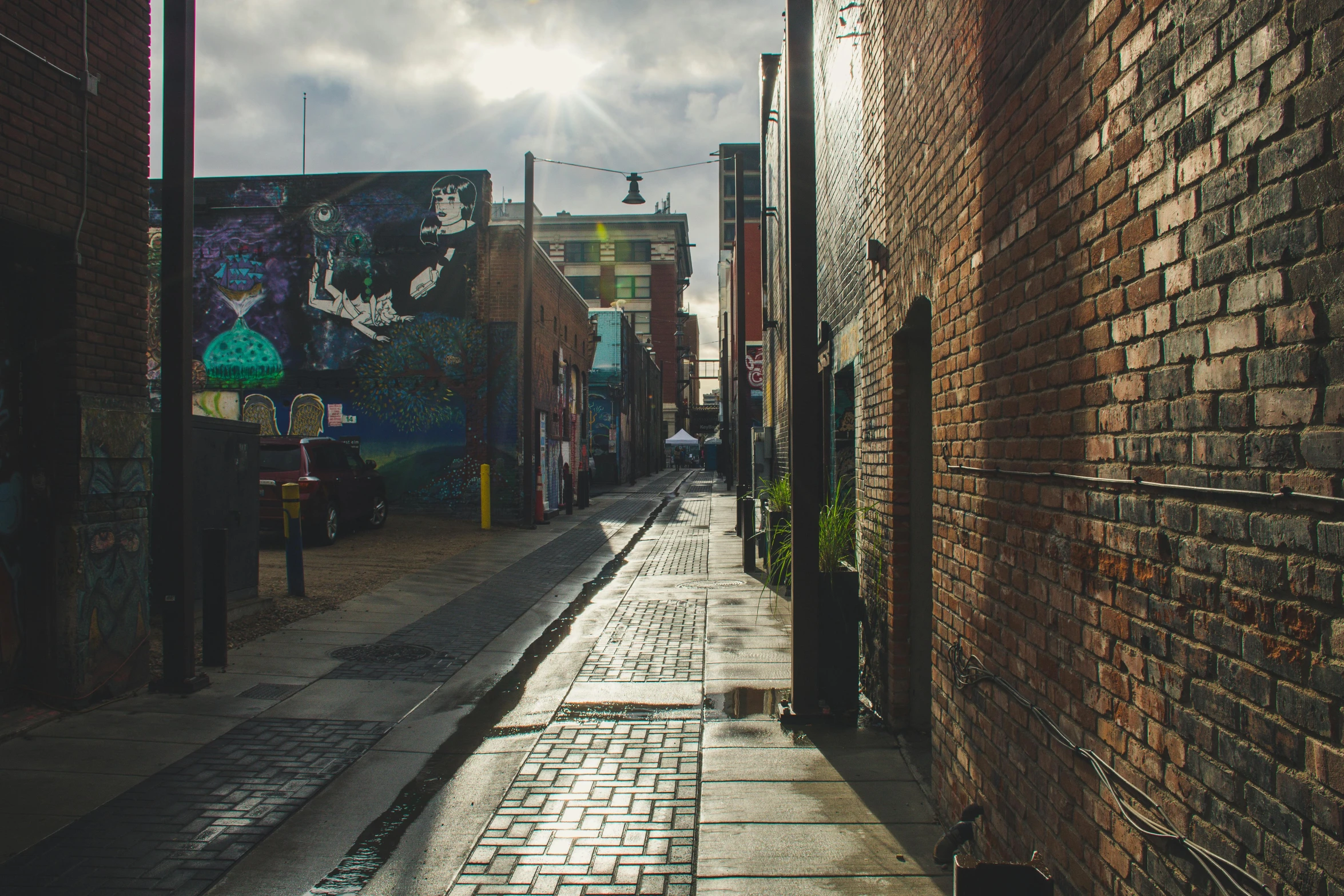 a cobblestone street lined with brick buildings, a photo, unsplash, graffiti, background image, manchester, sunlit, rain lit