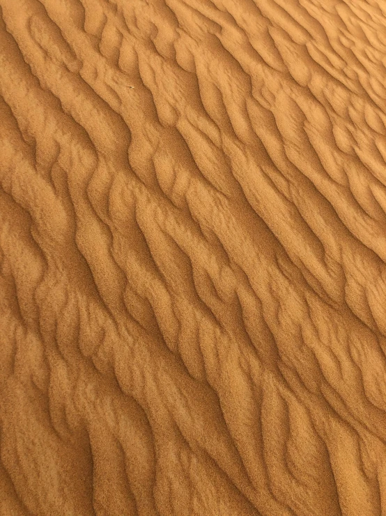 a person riding a surfboard on top of a sandy beach, up close, the desert, clay material, up-close