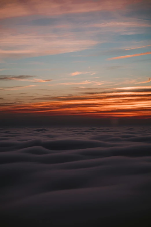 an airplane flying above the clouds at sunset, by Matt Cavotta, pexels contest winner, layered fog, today\'s featured photograph 4k, looking onto the horizon, blanket of fog