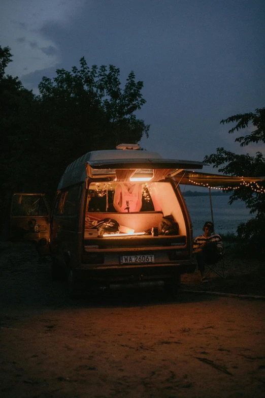 a camper van parked on the side of the road at night, by Attila Meszlenyi, people outside eating meals, lake view, cinematic morning light, vendors