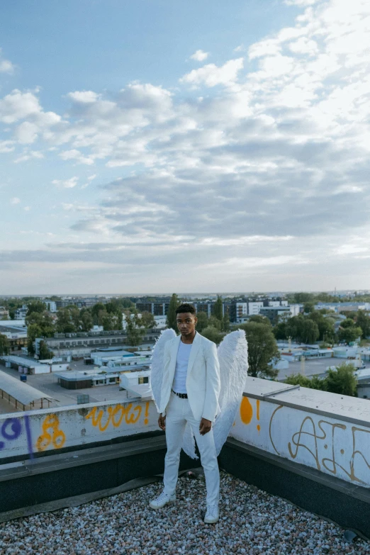 a man in a white suit standing on a roof, an album cover, by Niko Henrichon, unsplash, happening, young wan angel, berlin fashion, xxxtentacion, wide angel shot