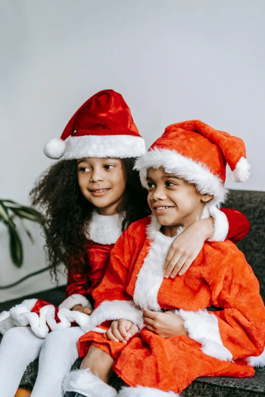 a couple of kids sitting on top of a couch, wearing a santa hat, diverse outfits, profile image, robes