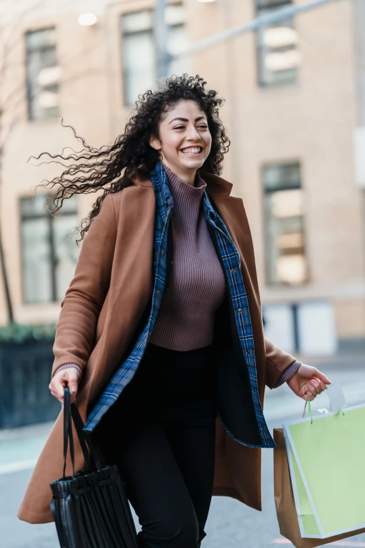 a woman walking down the street carrying shopping bags, pexels contest winner, renaissance, dark short curly hair smiling, wearing a long coat, young middle eastern woman, wavy hair spread out