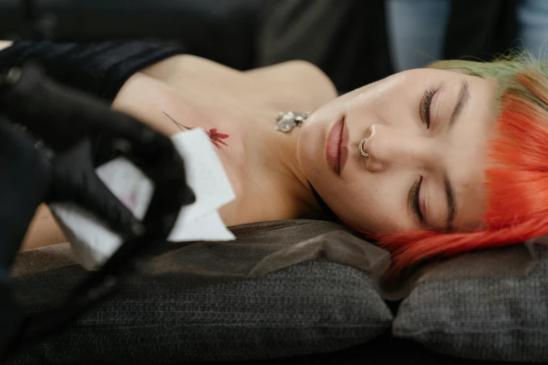 a woman with red hair laying on a couch, a tattoo, trending on pexels, spraying blood, flat colour, nose piercing, synthetic skin