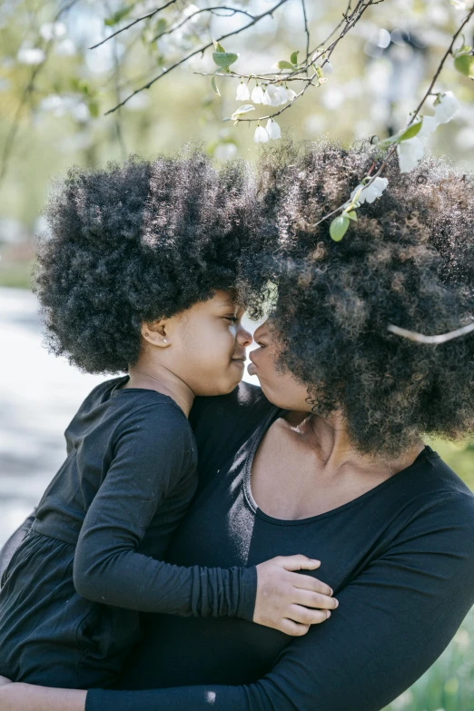 a woman holding a child in her arms, pexels contest winner, natural hair, deep black roots, lush green, queen