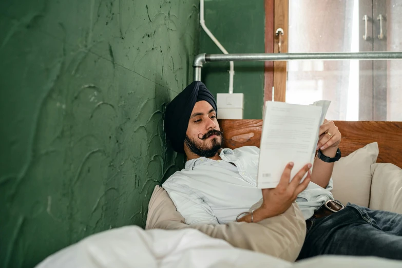 a man laying in bed reading a book, inspired by Manjit Bawa, in australia, profile image, fan favorite, in small room