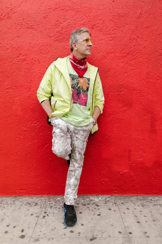 a man leaning against a red wall, an album cover, inspired by Marc Tetro, trending on pexels, neo-fauvism, multilayered outfit, gray haired, neon yellow madhubani, full body photograph