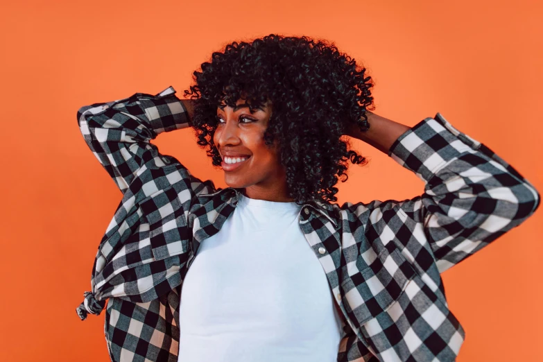 a woman wearing a black and white checkered shirt, trending on pexels, hurufiyya, wig, vibrant orange, avatar image, curls