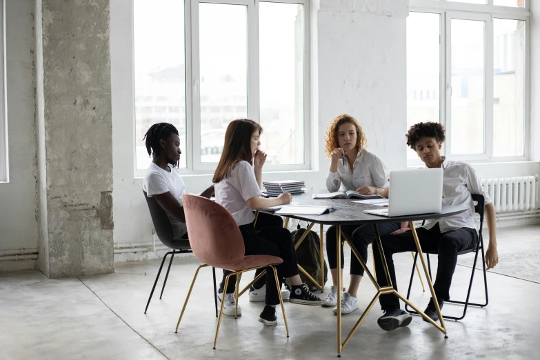 a group of people sitting around a table with laptops, by Emma Andijewska, pexels contest winner, sitting in an empty white room, sustainable materials, set inside of office, female