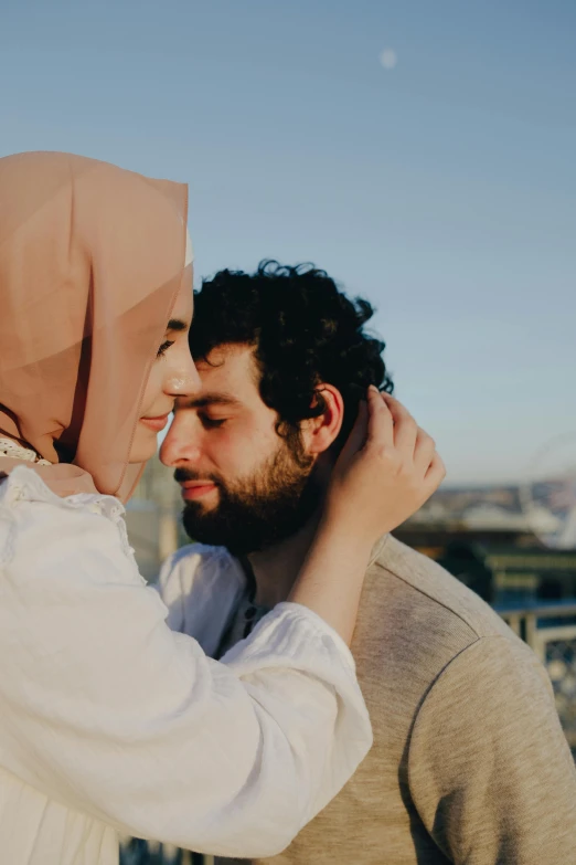 a man and a woman standing next to each other, by Ismail Acar, trending on pexels, hurufiyya, embracing, cheeks, afternoon, covered