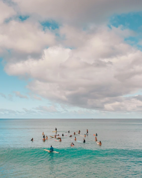 a group of people swimming in the ocean, standing on surfboards, photo of the middle of the ocean, kauai, skies