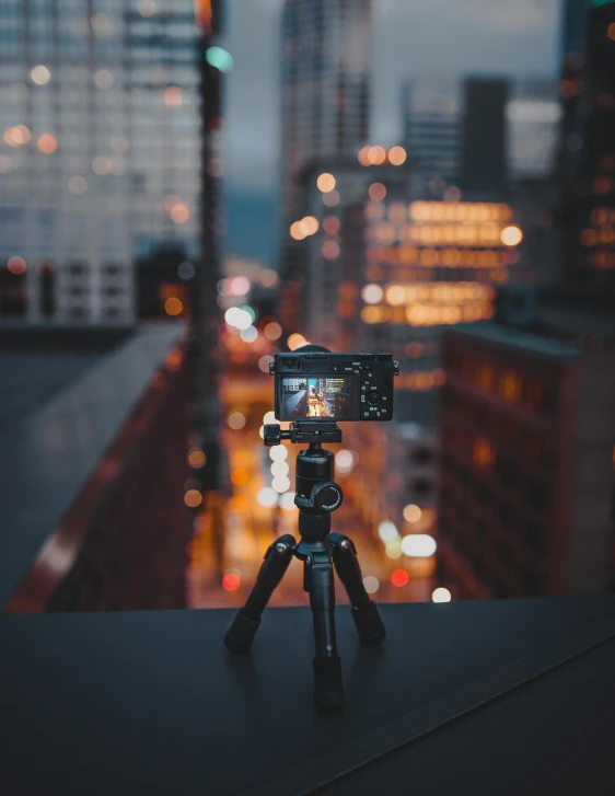 a tripod sitting on top of a building next to a city, a picture, unsplash contest winner, hasselblad film bokeh, on a dark background, instagram picture, sony a7