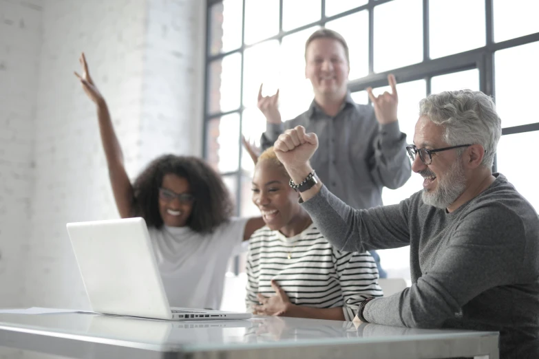 a group of people sitting around a table with a laptop, cheering, profile image, artsationhq, unblur