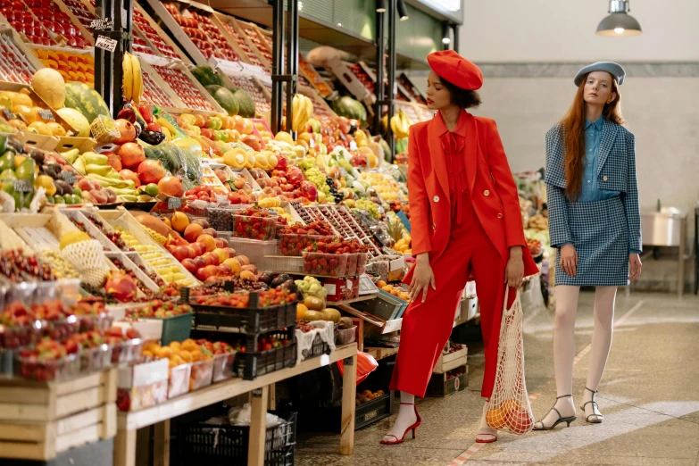 a couple of women standing next to each other in front of a fruit stand, a digital rendering, by Julia Pishtar, pexels, red suit, red hat, inside a supermarket, a woman wearing red high heels