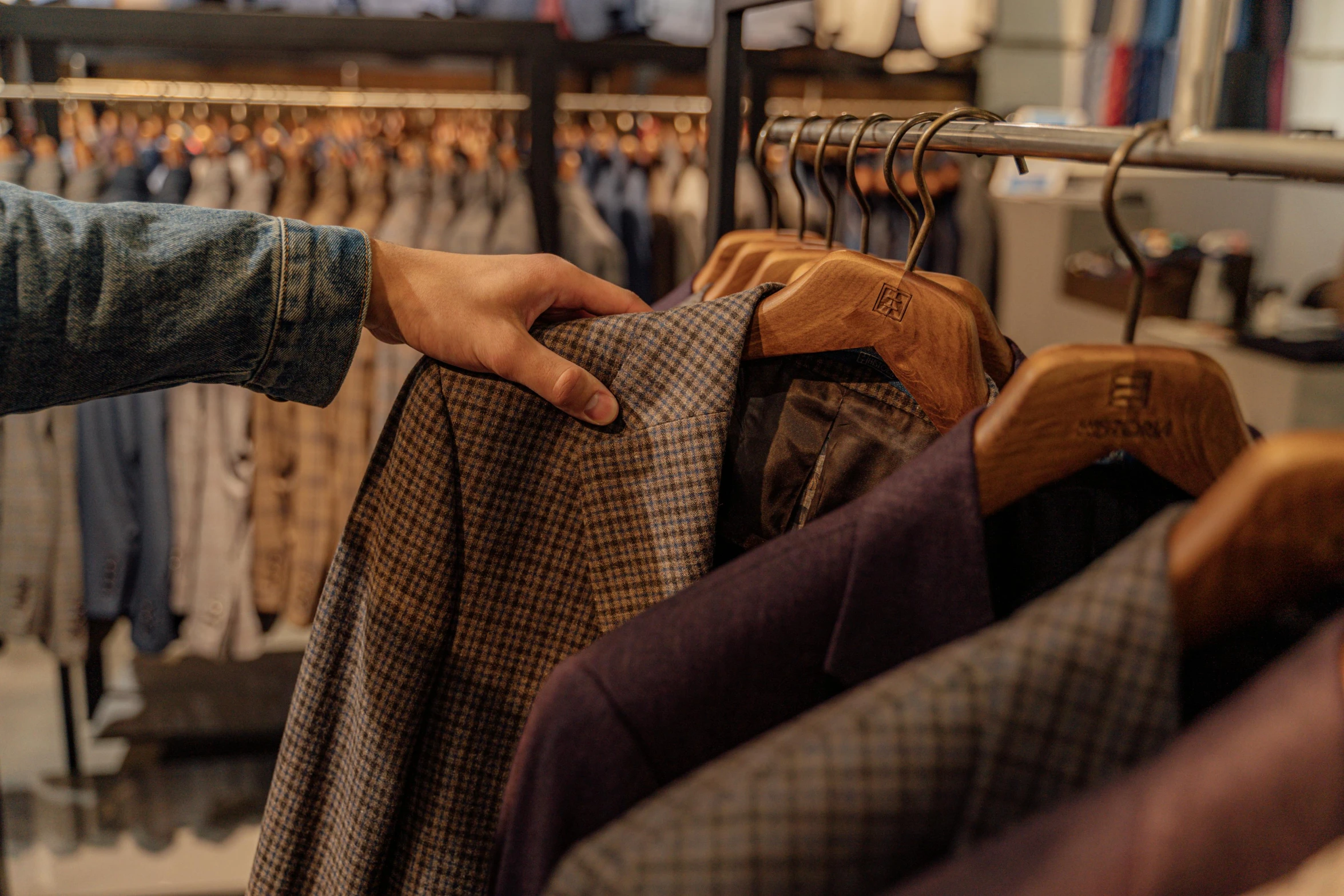 a person standing in front of a rack of clothes, trending on pexels, private press, wearing a worn out brown suit, people shopping, thumbnail, over the shoulder