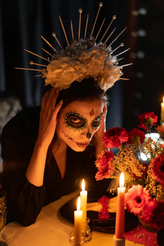 a woman in day of the dead makeup sitting at a table with candles, inspired by Kahlo, vanitas, headpiece, film still of emma watson, holiday season, concert