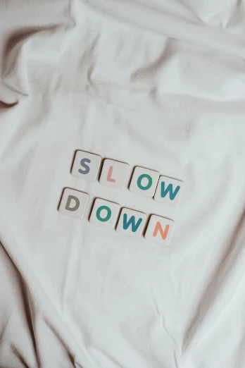 a white shirt with the words slow down on it, by Thomas Millie Dow, unsplash contest winner, funny jumbled letters, game top down view, sleepwear, 2000s photo