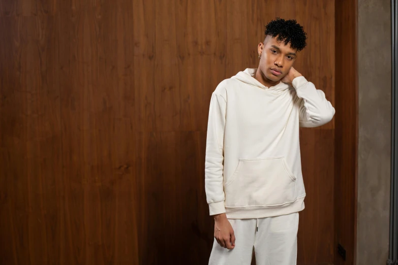 a man standing in front of a wooden wall, an album cover, inspired by Frank Mason, trending on pexels, renaissance, beige hoodie, wearing white pajamas, ashteroth, thumbnail