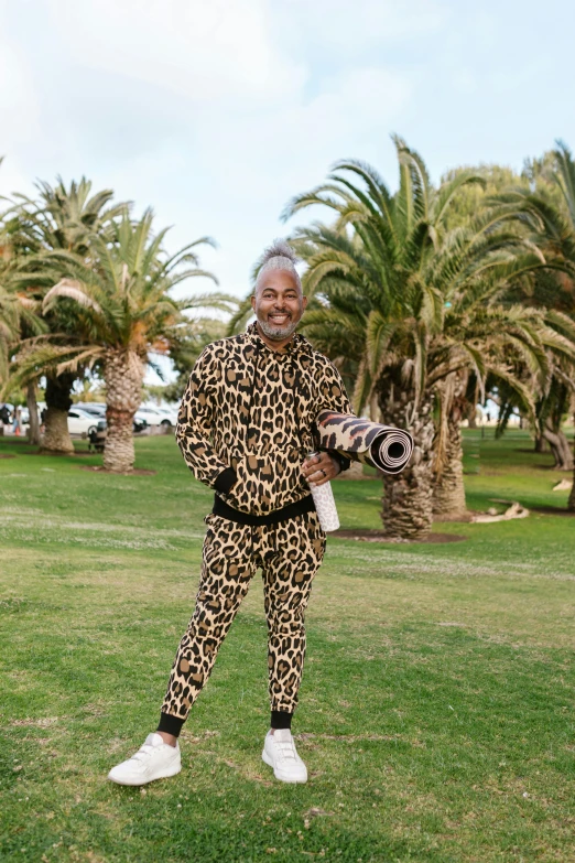 a man standing on top of a lush green field, wearing animal skin clothing, wearing disco suit, gray haired, jamal campbell