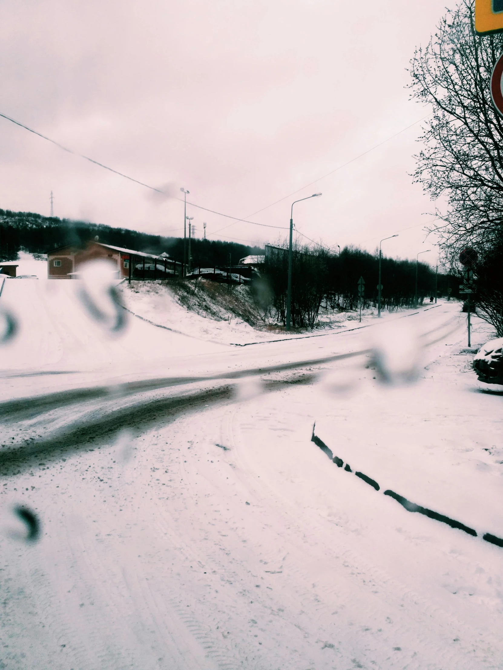 a street sign sitting on the side of a snow covered road, an album cover, pexels contest winner, hurufiyya, 000 — википедия, small town surrounding, viewed through the cars window, disposable camera photo