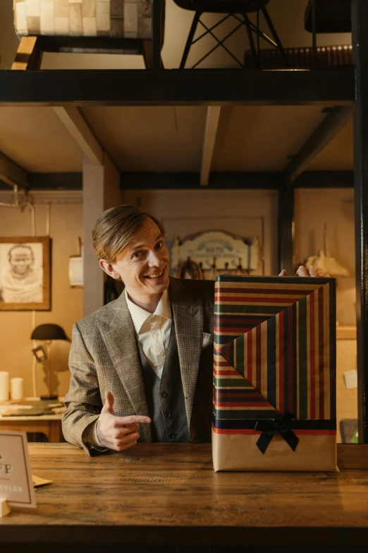 a man in a suit sitting at a table, an album cover, by Wes Anderson, harry potter at a tardis console, ignant, looking at the treasure box, official store photo