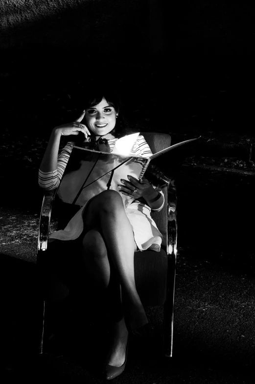 a woman sitting in a chair reading a book, an album cover, flickr, taken in the night, b&w!, pretty woman, nigth