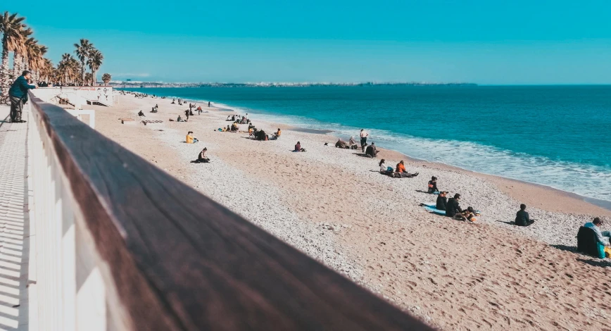 a group of people sitting on top of a sandy beach, pexels contest winner, lisbon, sea line, on a hot australian day, fall season