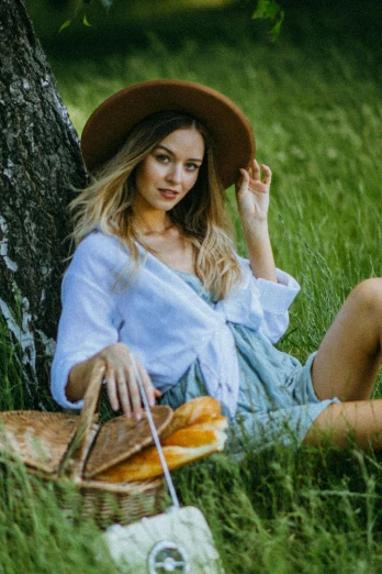 a woman sitting in the grass next to a tree, sydney sweeney, wearing straw hat, bread, 5 0 0 px models