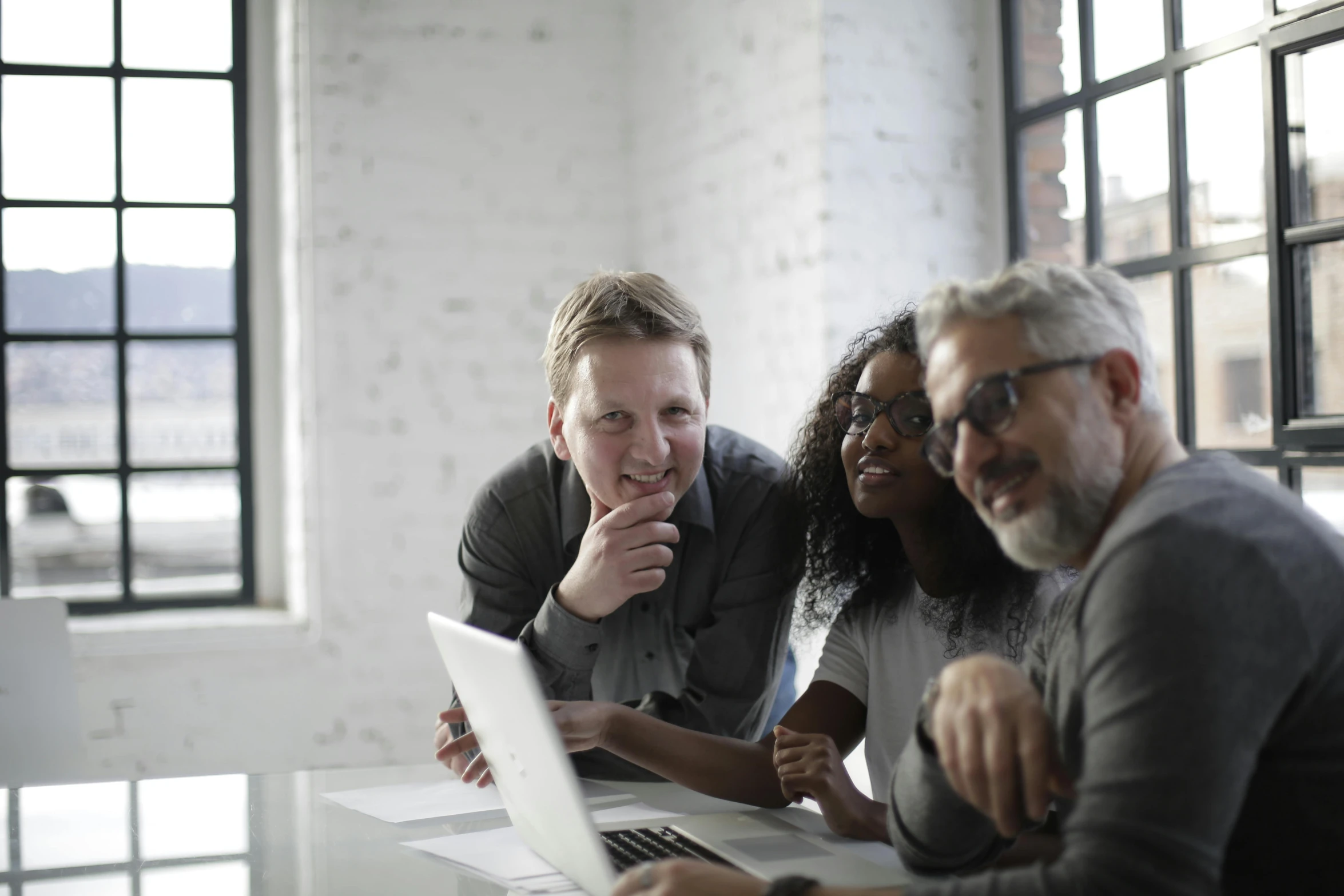 a group of people sitting around a table with a laptop