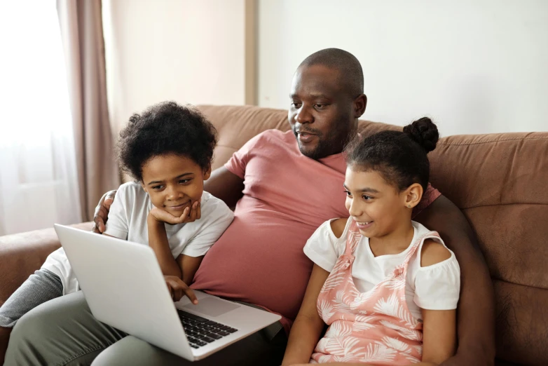 a man and two children sitting on a couch with a laptop, by Carey Morris, pexels, incoherents, black people, avatar image, school class, tv still