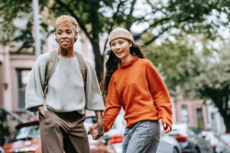 two people walking down the street holding hands, trending on pexels, antipodeans, long orange sweatshirt, mix of ethnicities and genders, her friend, sydney park