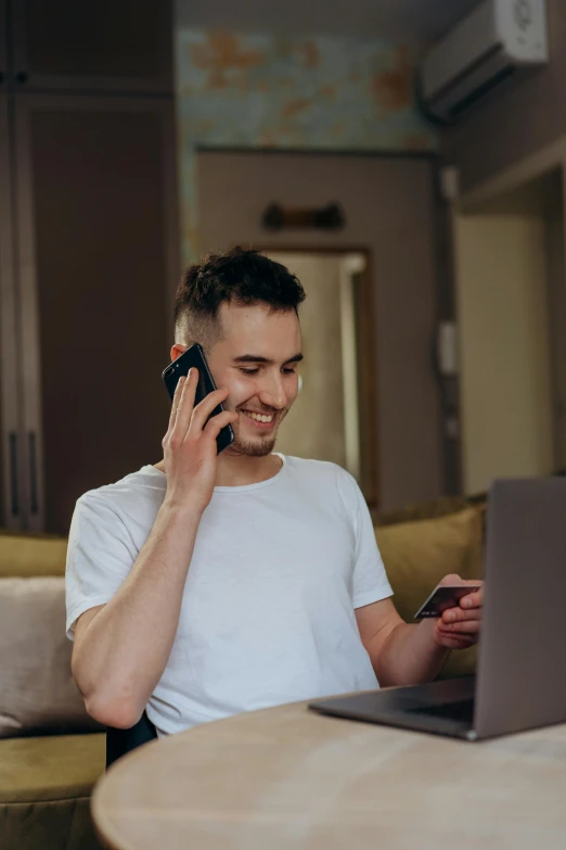 a man sitting on a couch talking on a cell phone, in front of a computer, selling insurance, at checkout, promotional image