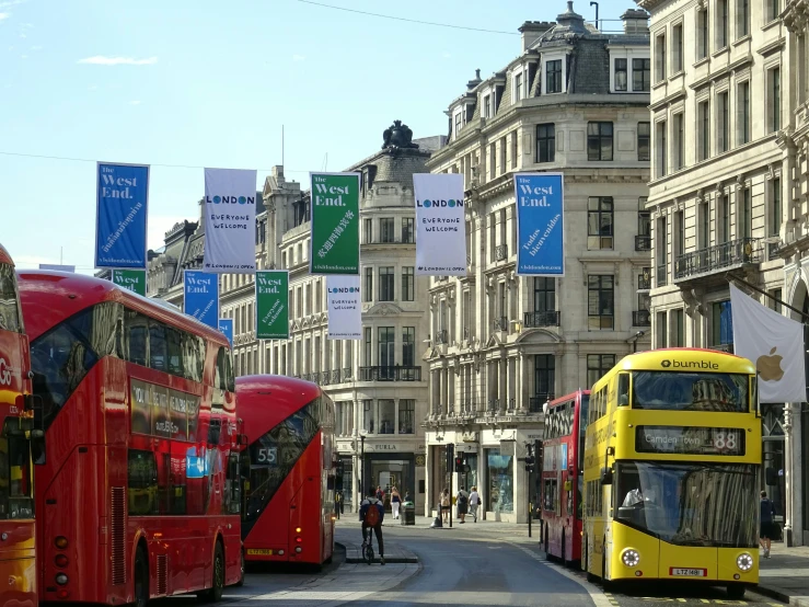 a couple of double decker buses driving down a street, a photo, by David Donaldson, temporary art, cloth banners, billboard image