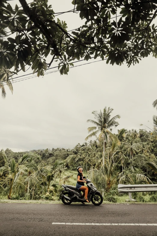 a man riding on the back of a motorcycle down a road, a picture, unsplash, sumatraism, banana trees, panoramic view of girl, 🚿🗝📝