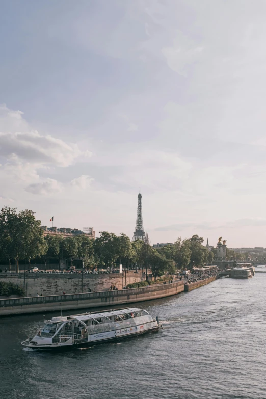 a boat traveling down a river next to the eiffel tower, a photo, trending on unsplash, paris school, panoramic view, trending on vsco, late afternoon light, tall stone spires