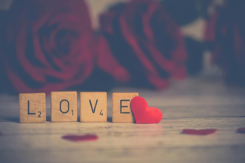 a wooden block with the word love spelled on it, pexels, romanticism, red roses, thumbnail, blurred, 🚿🗝📝