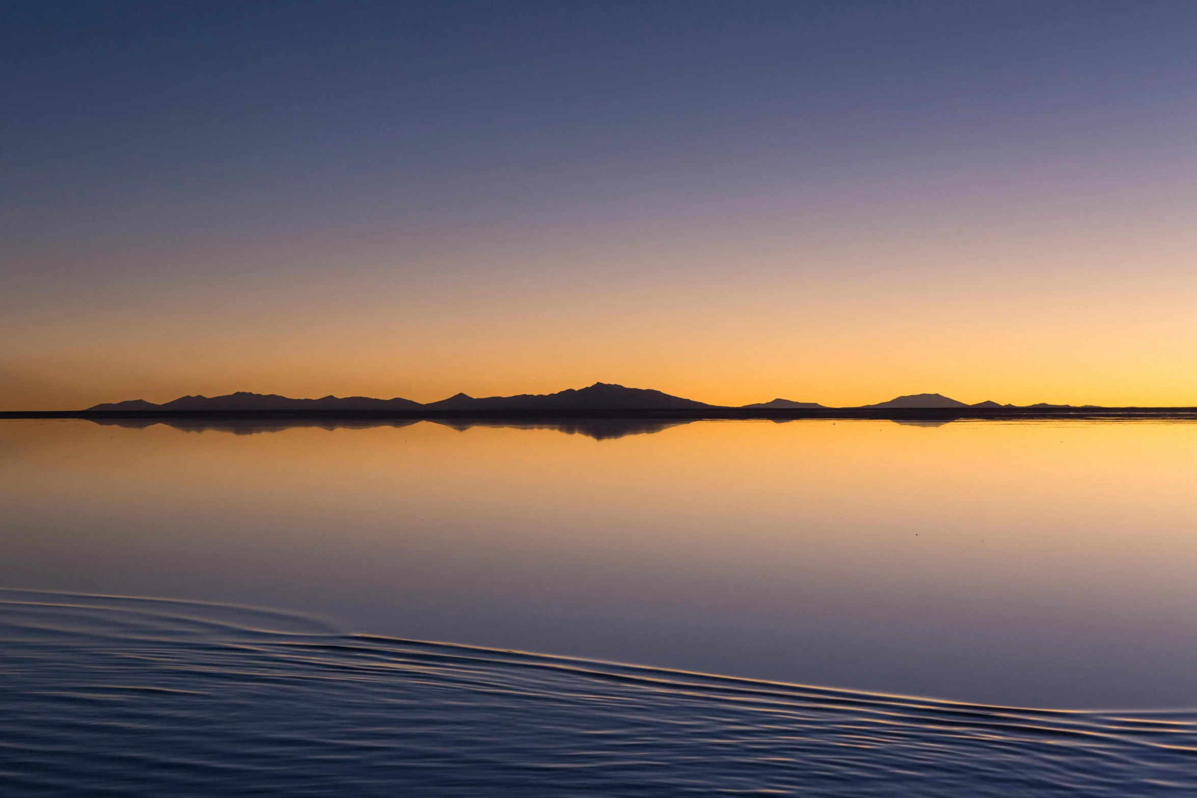 a large body of water with mountains in the background, unsplash contest winner, minimalism, 8k hdr sunset lit, mirage, new zealand, islands on horizon