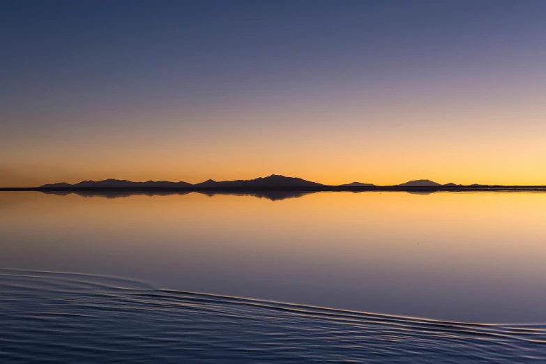 a large body of water with mountains in the background, unsplash contest winner, minimalism, 8k hdr sunset lit, mirage, new zealand, islands on horizon