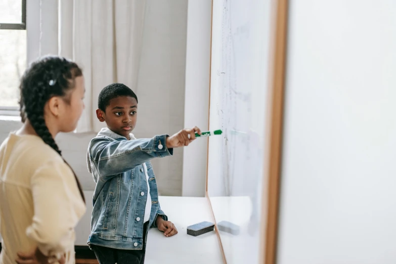 a boy and a girl standing in front of a whiteboard, by Emma Andijewska, pexels contest winner, playing games, pointing, black chalk, riyahd cassiem