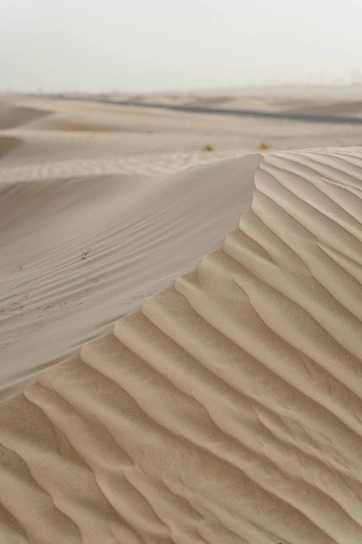 a person riding a motorcycle in the desert, trending on unsplash, land art, sand texture, serrated point, folds, grey