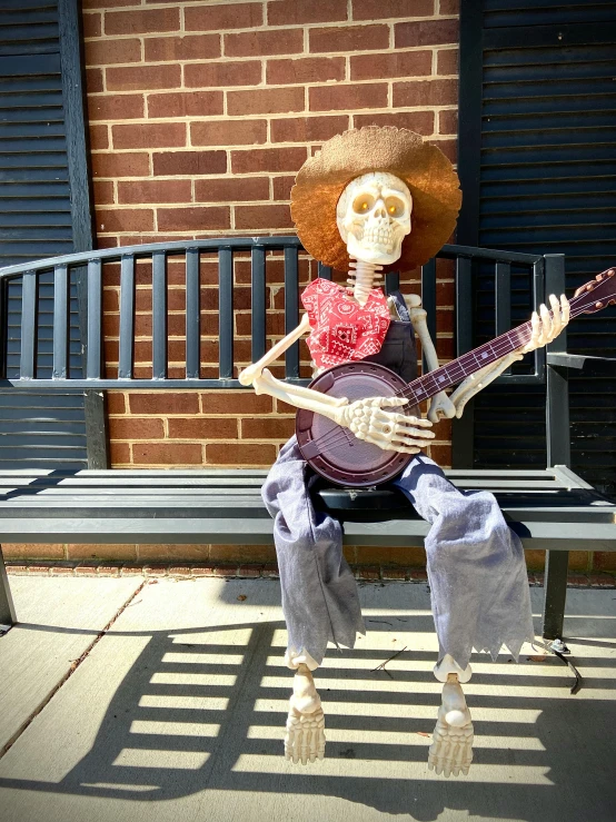 a skeleton sitting on a bench with a guitar, wearing a straw hat and overalls, from wheaton illinois, 2019 trending photo, pose 4 of 1 6